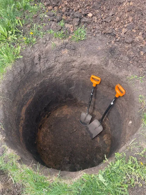 Круглый котлован под кольцо колодца с лопатами